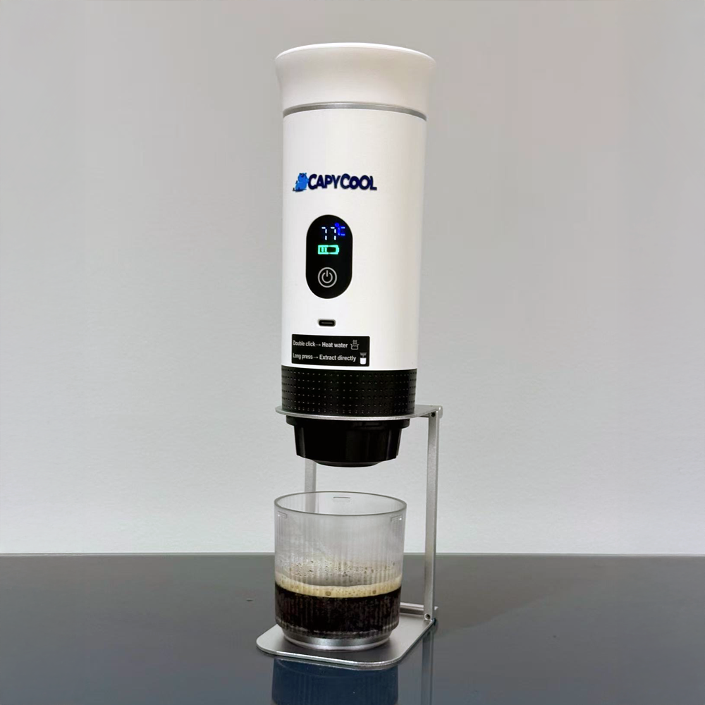 White CapyCool portable coffee machine brewing espresso into a glass, with a digital display.