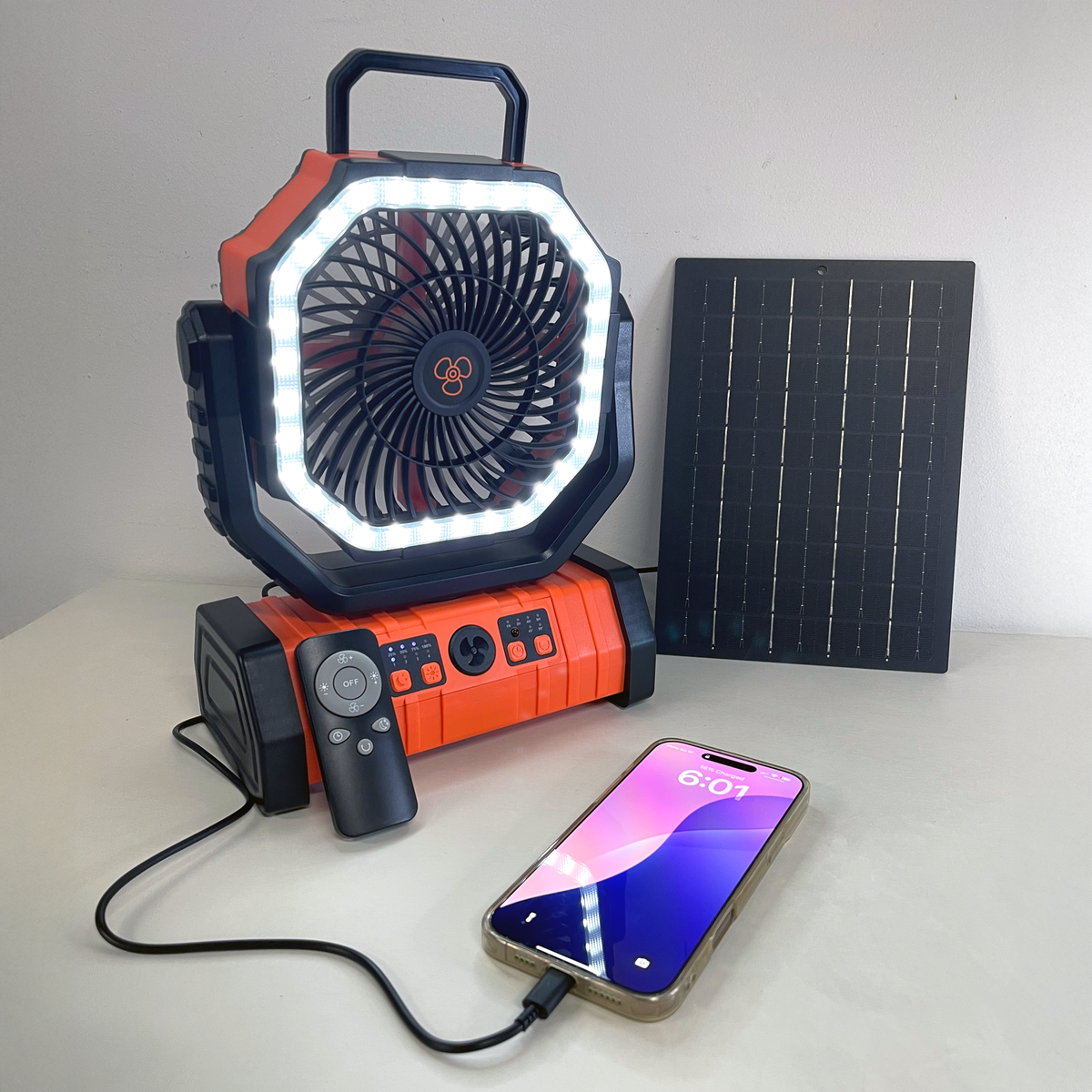 Orange portable camping fan with LED light, solar panel, remote, and phone charging