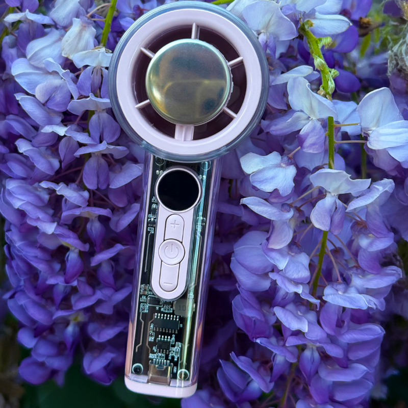 Pink and clear CrystalCool Turbo fan with transparent mecha design and ice compress, against purple wisteria.